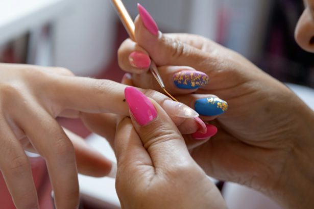 closeup of manicurist doing nail art to a client