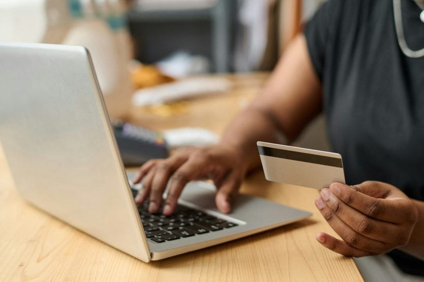 Hand of young African American female buyer with card ordering goods online