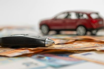 key and red toy car on pile of euro banknotes, buy or sell a car, rent a car or insurance concept